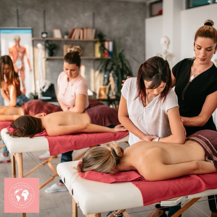 Alliance of Beauty Practitioners Beautician instructing 3 students on massage techniques, 3 females on treatment beds