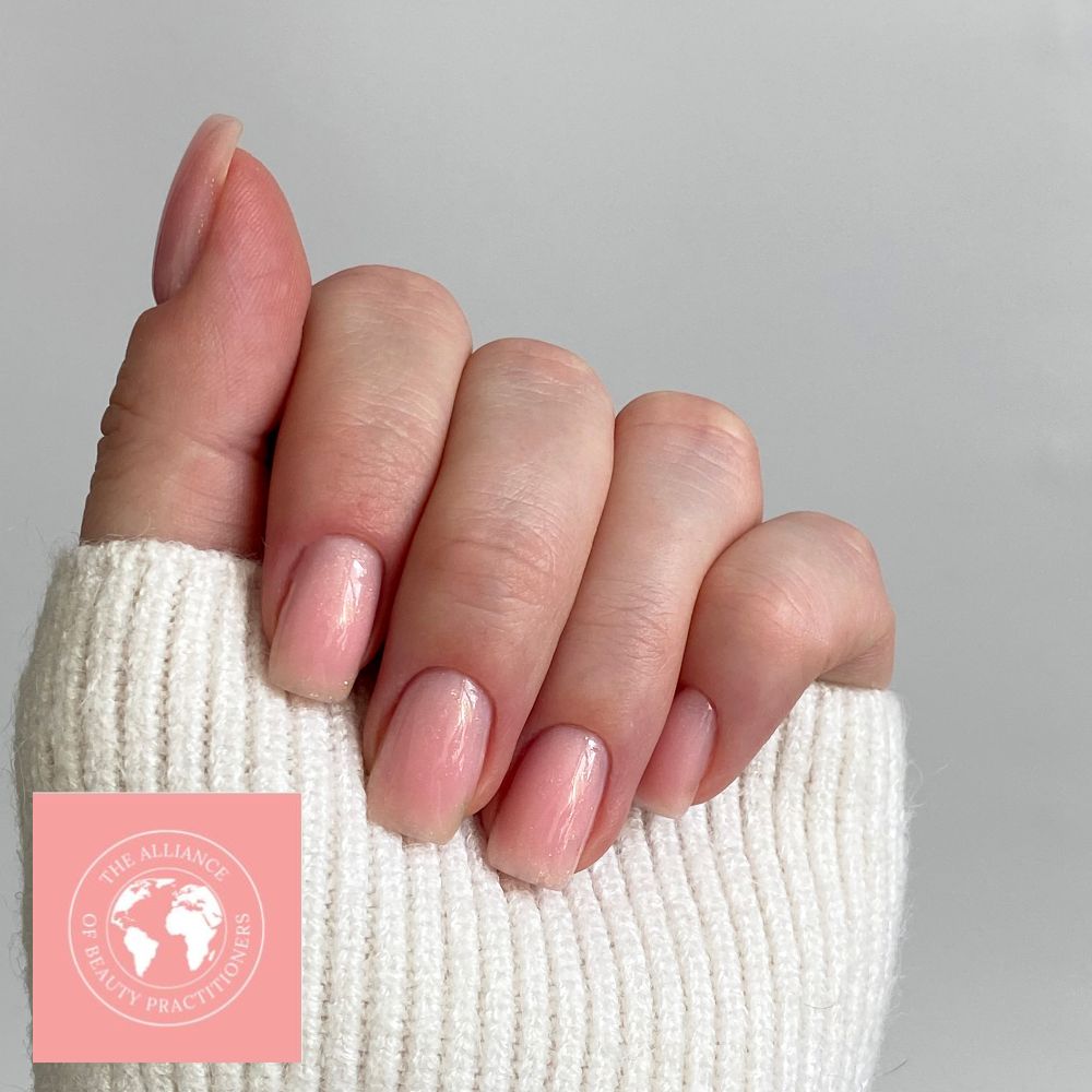 Soap nails trend includes natural pale pink polish like the one on this hand, with a cream jumper