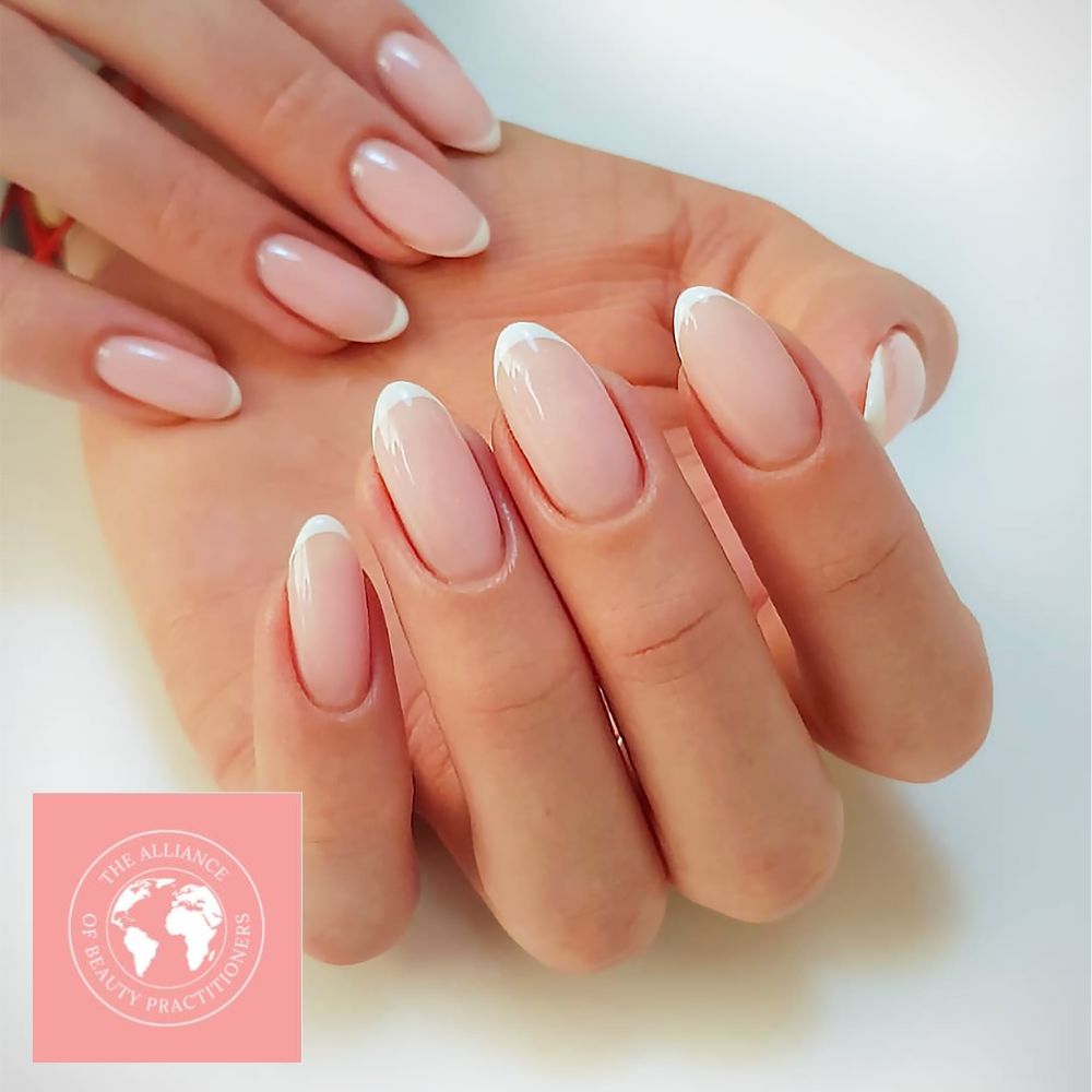 Two hands showing a very pale, almost white, clean nail polish, typical of the soap nails trend with a french tip